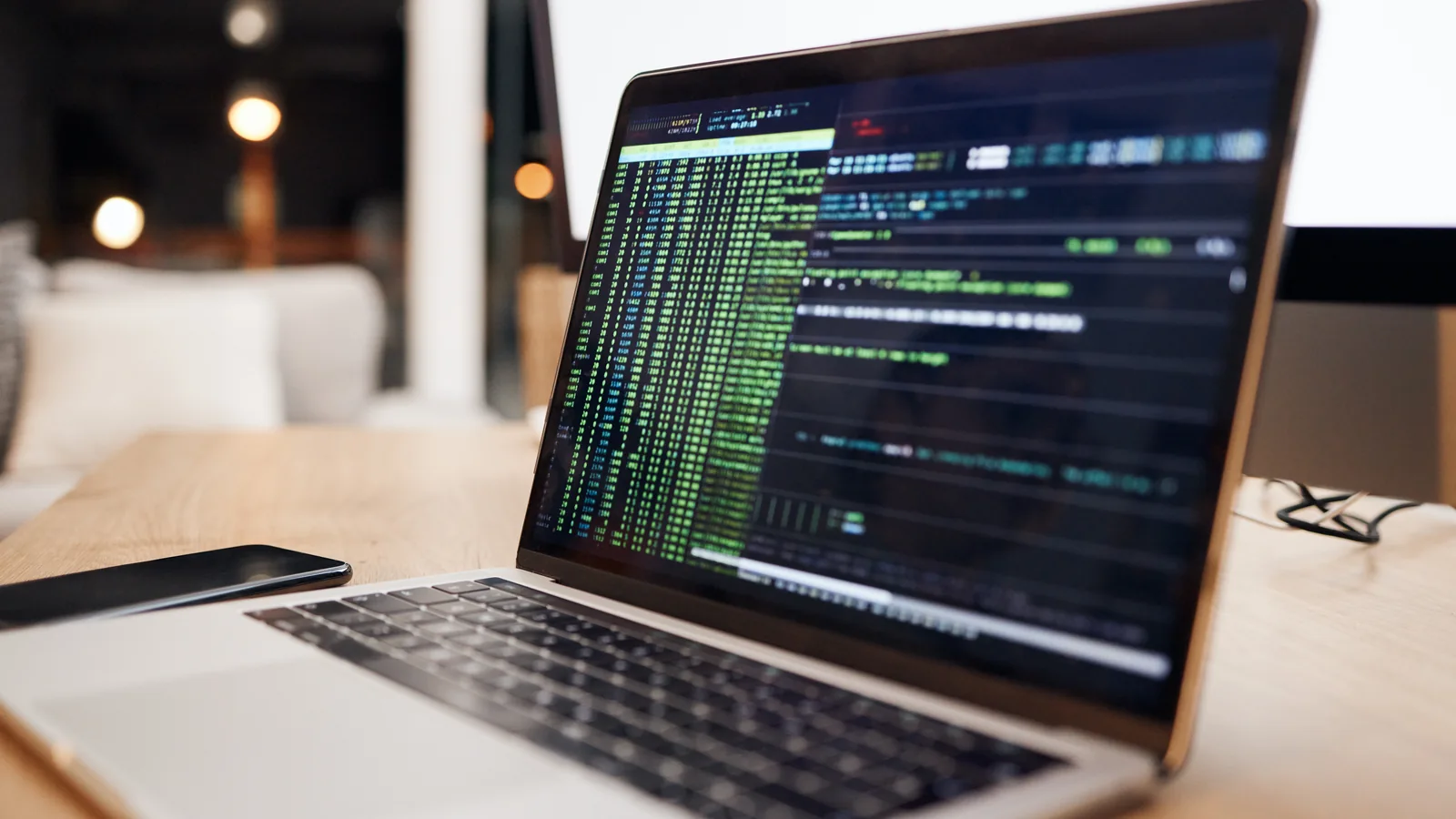 Un ordinateur portable affiche des lignes de code sur un bureau.