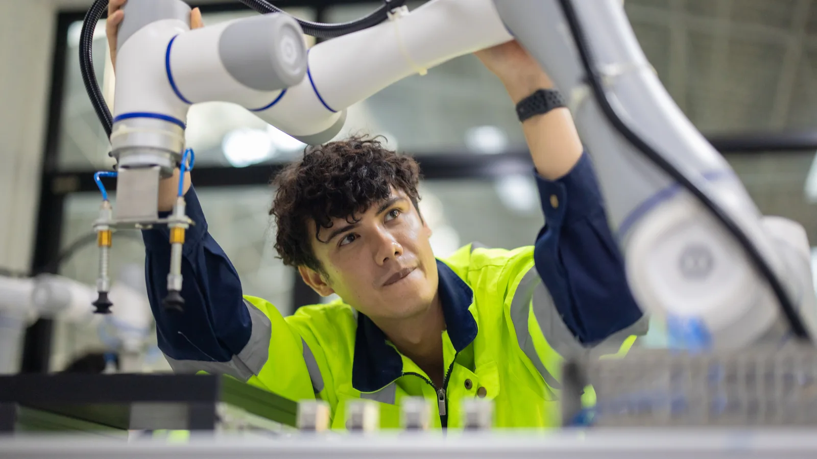 Une personne examine un bras robotisé dans un atelier technique.