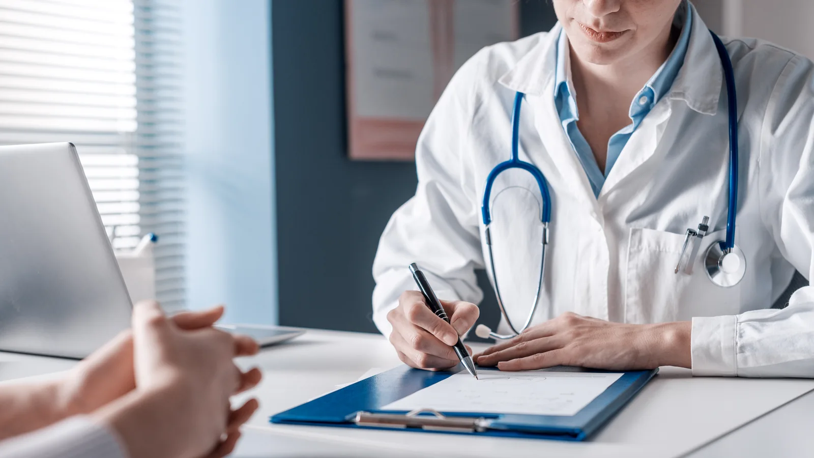 Un médecin en blouse blanche remplit un document pendant une consultation.