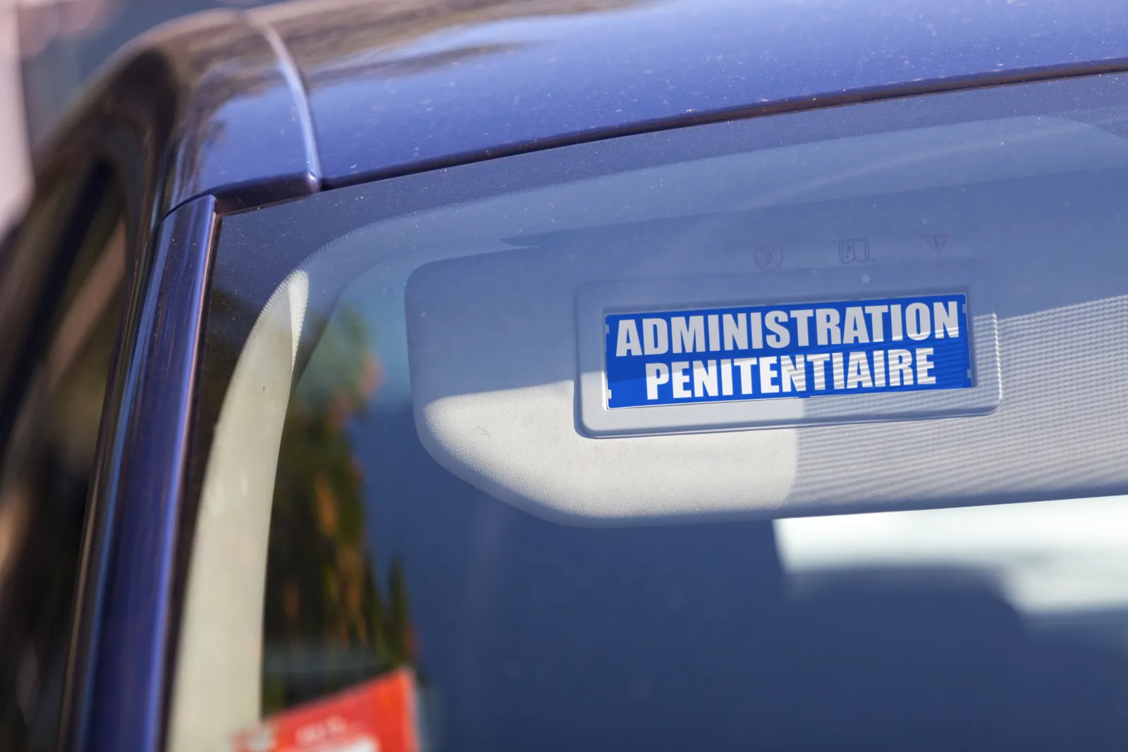Inscription Administration pénitentiaire visible derrière le pare-brise d’un véhicule.