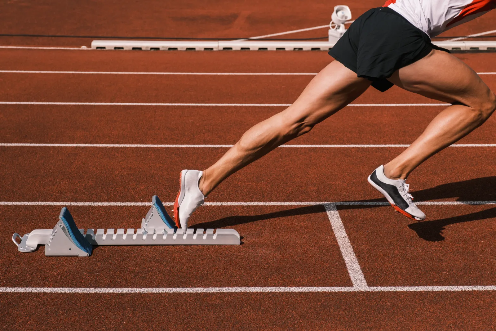 Un athlète s’élance des starting-blocks sur une piste d’athlétisme.