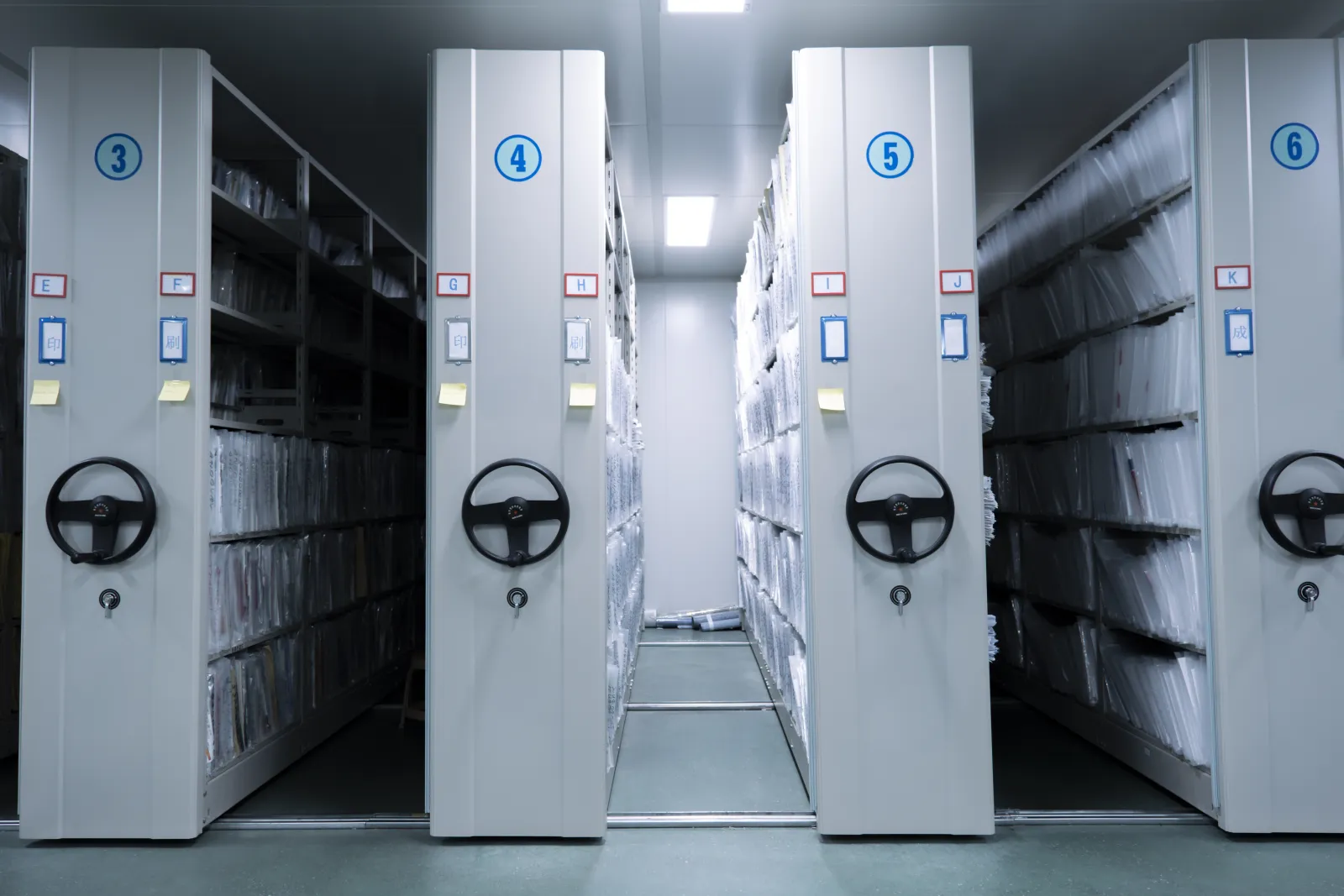 Des dossiers sont rangés dans des rayonnages mobiles d’une salle d’archives.
