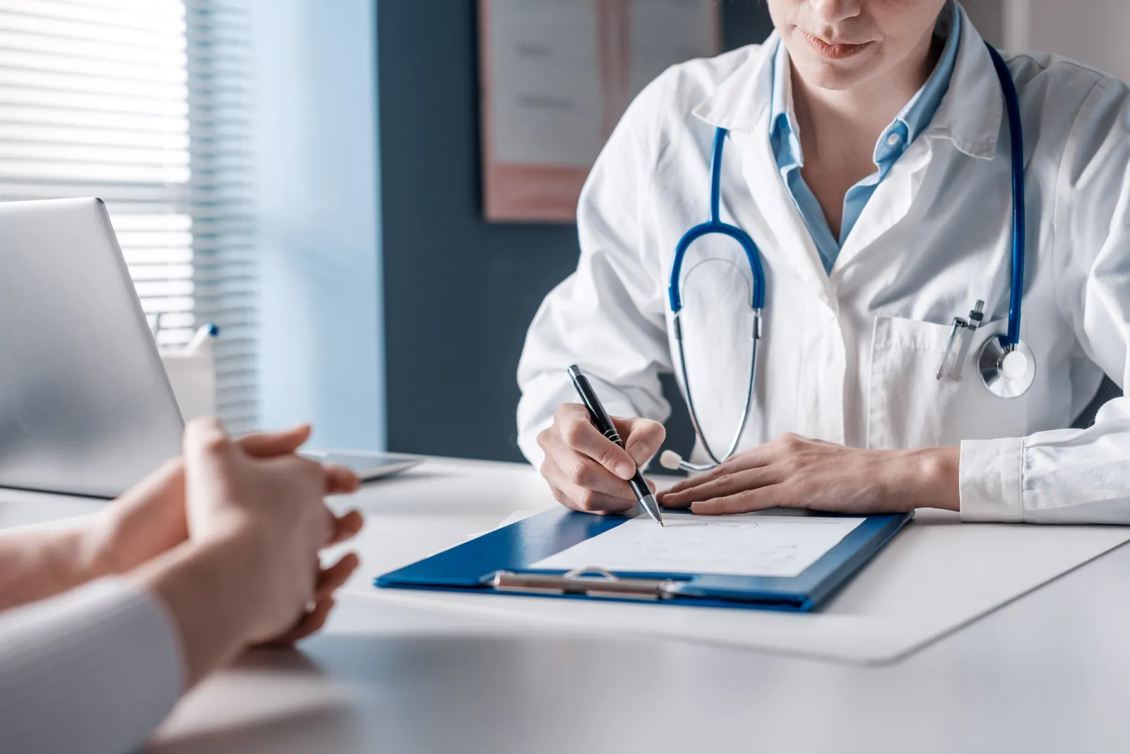 Un médecin prend des notes pendant une consultation.