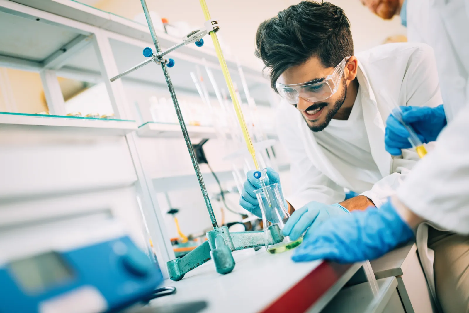 Une manipulation de chimie avec de la verrerie de laboratoire, des gants et des lunettes de protection.