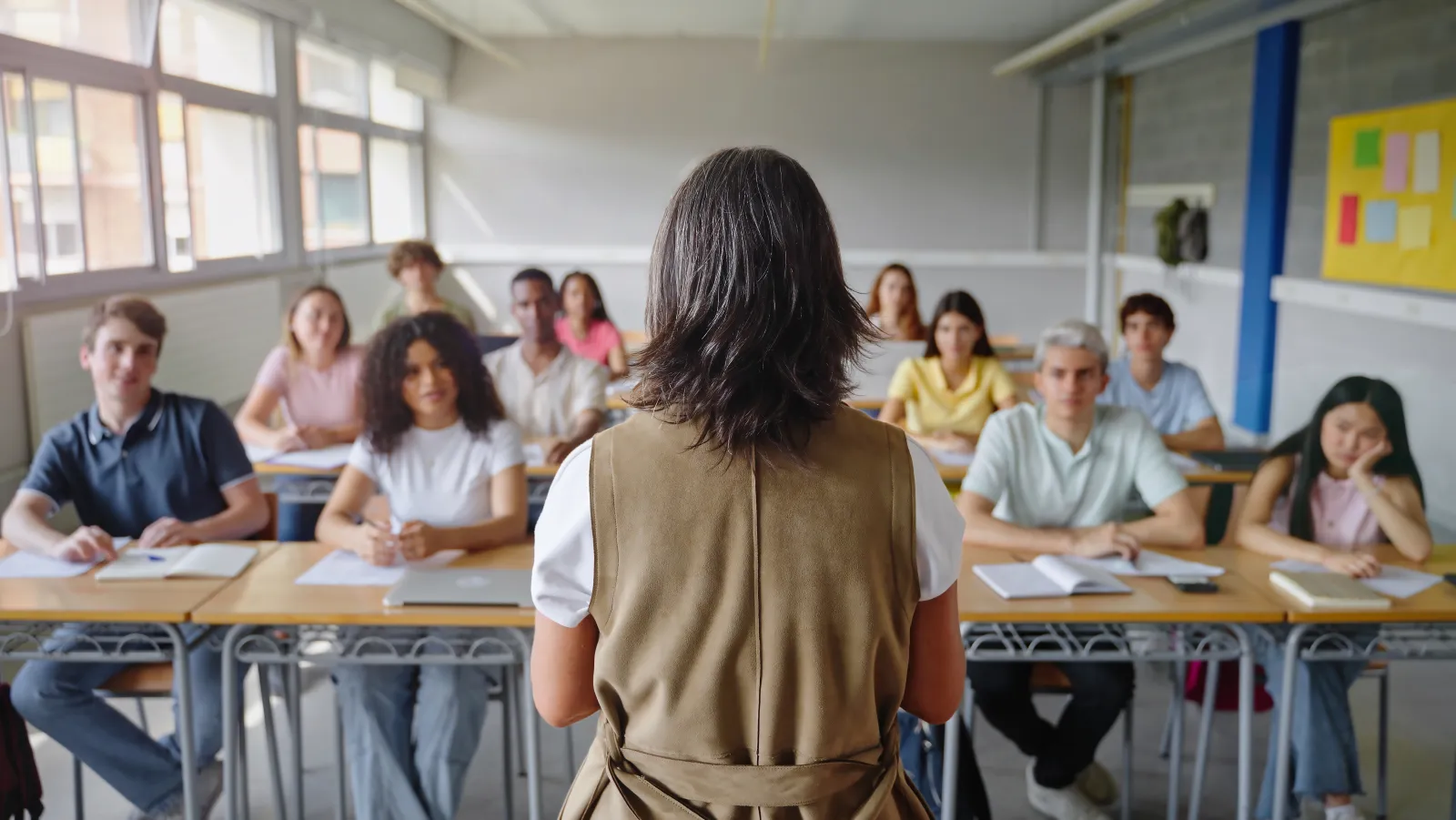 Une enseignante face à des élèves installés dans une salle de classe.