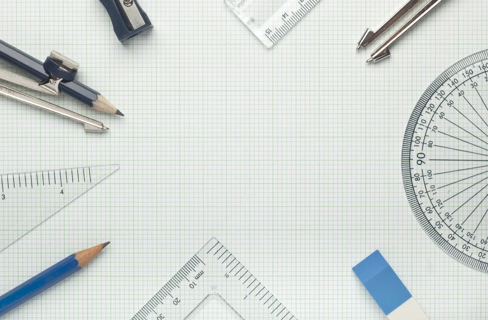 Compas, rapporteur, règles et crayons disposés sur du papier quadrillé.