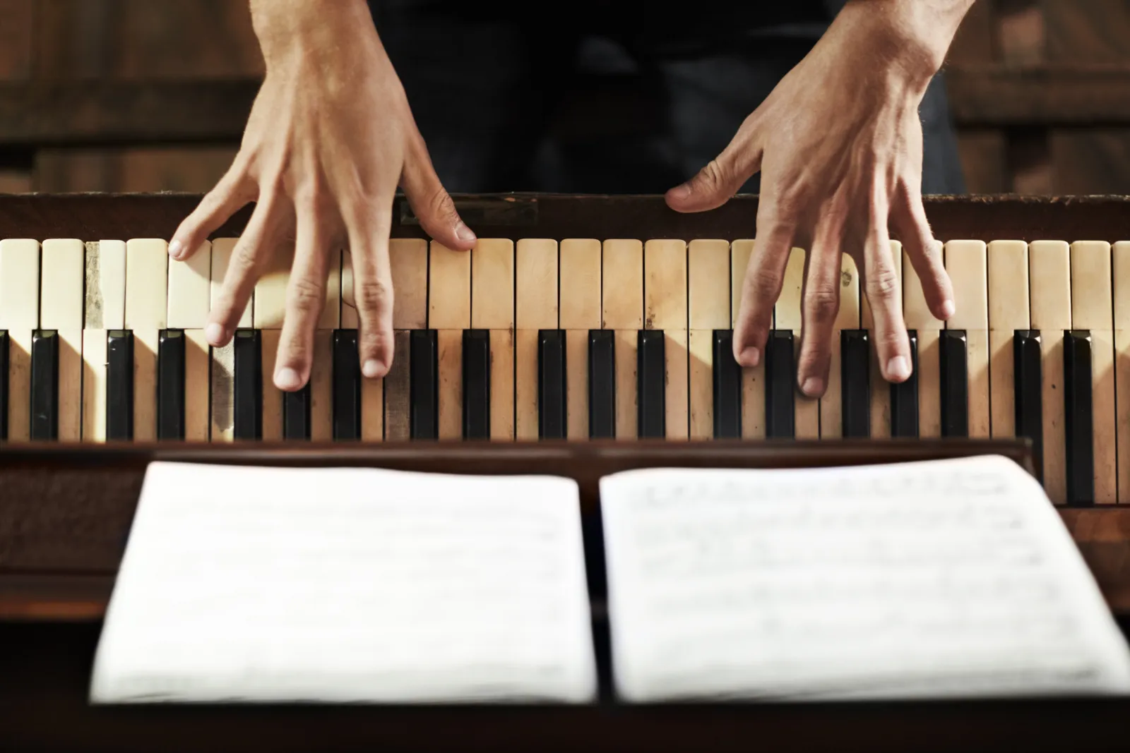 Les mains d’un pianiste sur le clavier, devant une partition ouverte.