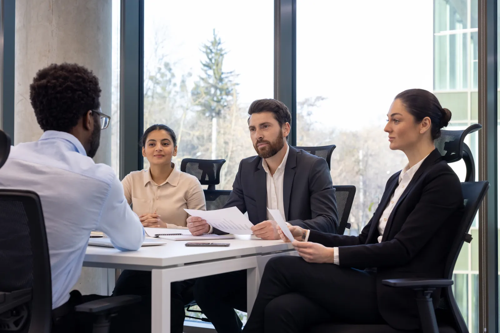 Un candidat échange avec trois interlocuteurs assis de l’autre côté d’une table.