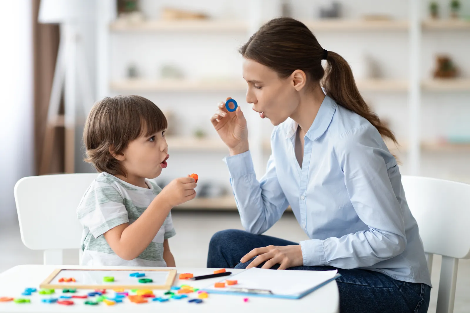 Une orthophoniste montre une lettre à un enfant pendant un exercice de prononciation.