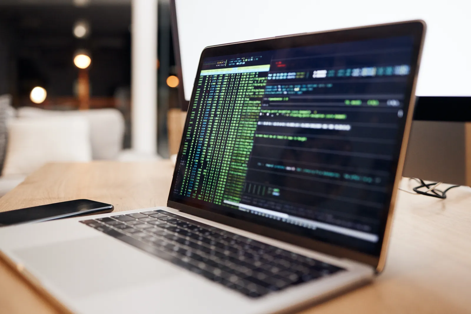 Un ordinateur portable affiche du code informatique sur un bureau.
