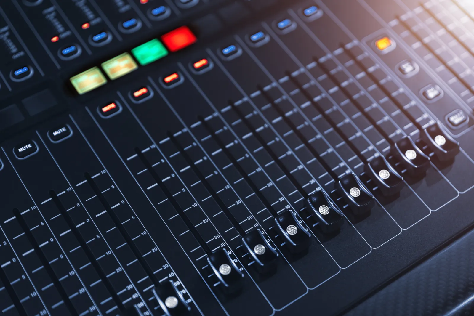 Faders et commandes lumineuses d’une console de régie sonore.