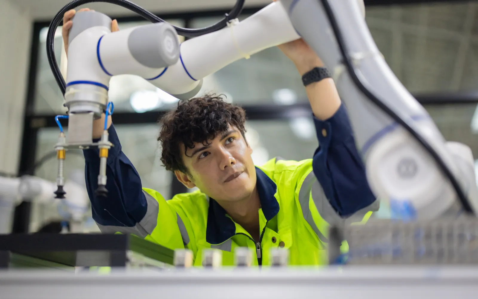Une personne examine un bras robotisé dans un atelier technique.