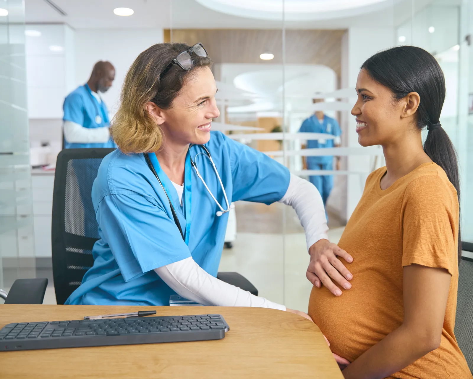 Une professionnelle de santé échange avec une femme enceinte dans une salle de consultation.